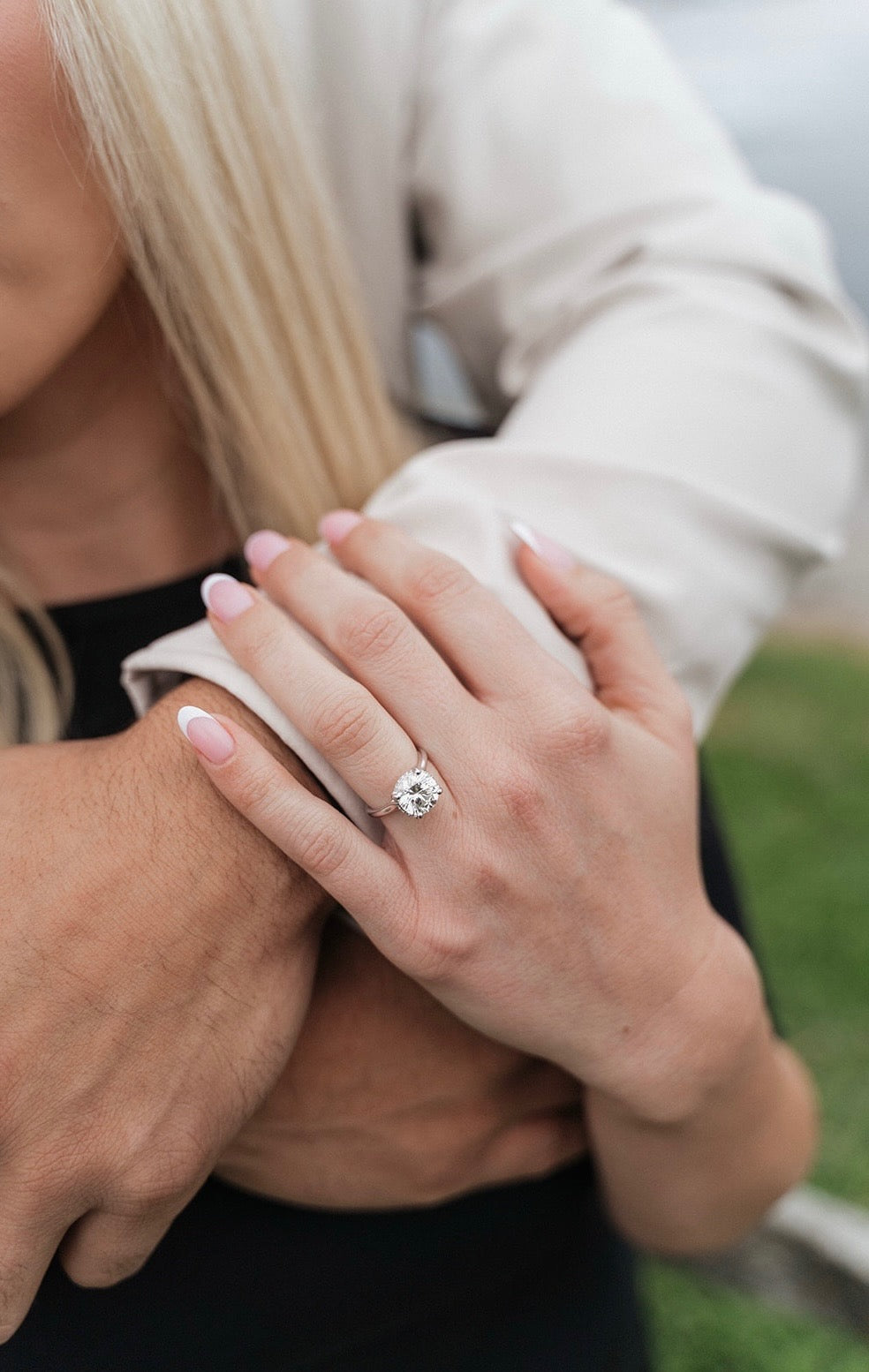 Round diamond engagement ring worn in an engagement portrait