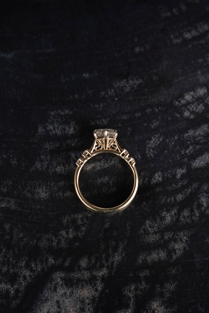 Side profile of a custom engagement ring in yellow gold on black velvet